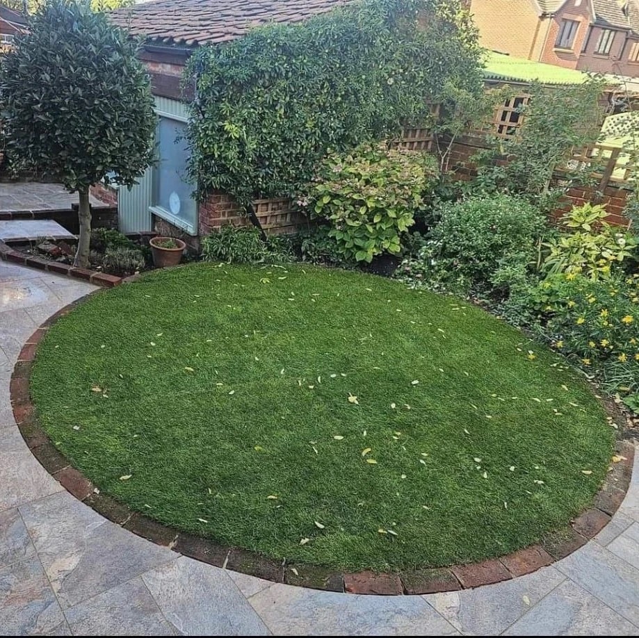 Artificial grass lawn with brick edging and stone paving