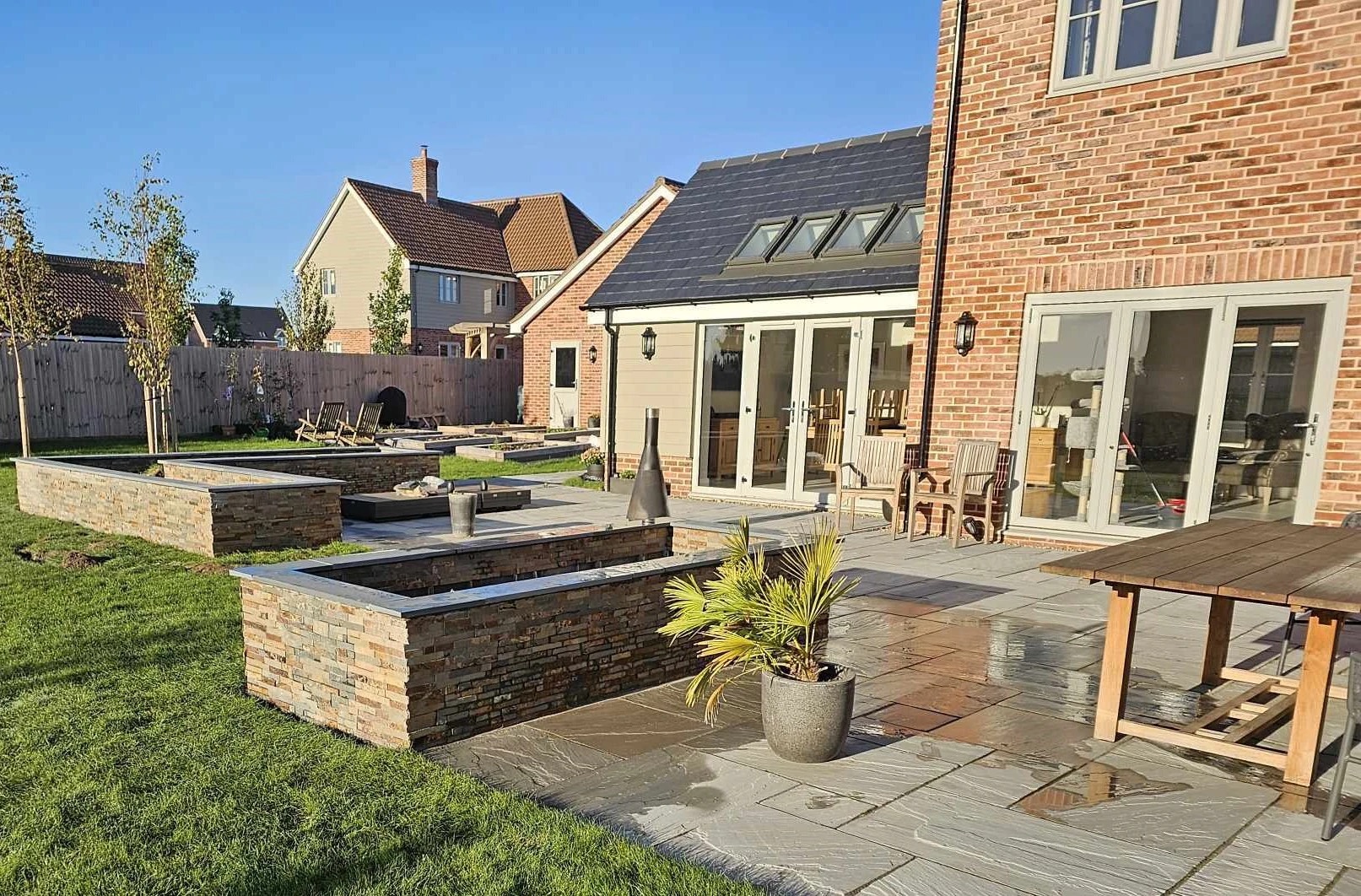 Indian sandstone patio with stone clad raised beds and water feature